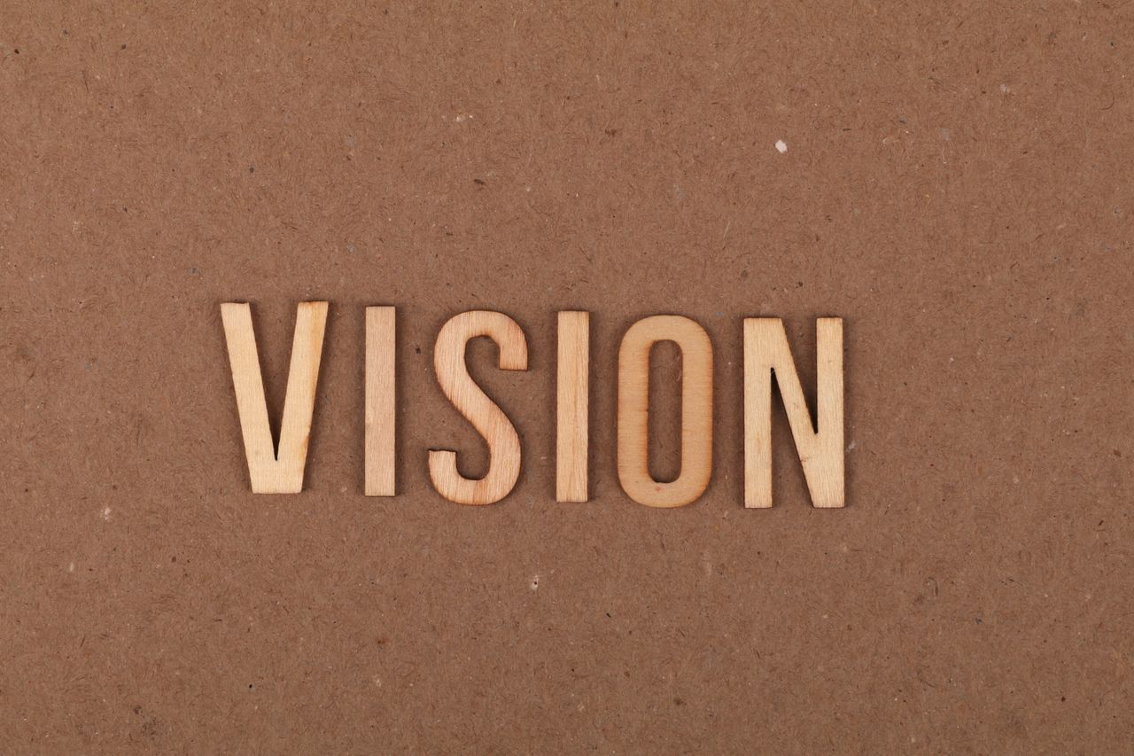 Wooden letters spelling 'VISION' on a textured cardboard surface.